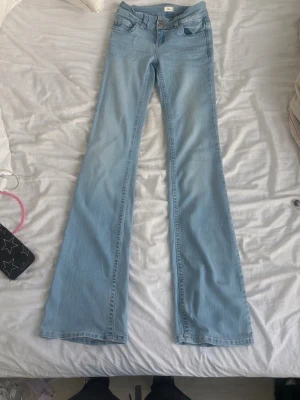 Ljusblå bootcut jeans med broderi - Säljer ett par ljusblå bootcut jeans med snyggt broderi på bakfickorna. Jeansen har klassisk femficksdesign och är tillverkade i denim med stretch. Perfekta för dig som gillar en retrostil och vill ha ett par jeans som sticker ut.