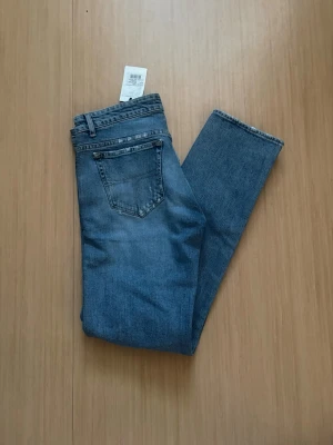 Blå tiger of Sweden jeans  - Säljer ett par klassiska blå jeans med rak passform och hög midja. Jeansen har fem fickor och bälteshällor. Materialet är denim i bomull och färgen är en tidlös mellanblå nyans. Perfekta till en avslappnad stil och även perfekta till sommaren!