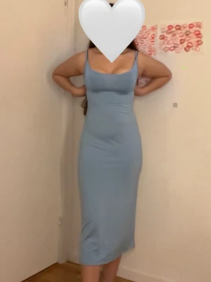 Ljusblå tight långklänning - Snygg ljusblå långklänning med smala axelband och figurnära passform. Klänningen är ärmlös och har en enkel, stilren design som passar perfekt till sommaren. Mjuk och stretchig känsla.
