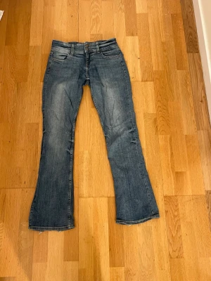 Blå bootcut jeans med slitningar - Snygga blå bootcut jeans med lätt slitna detaljer. Jeansen har låg midja och utsvängda ben. 