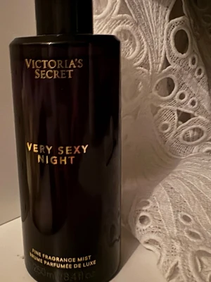 Victoria's Secret Very Sexy Night mist - En lyxig parfymmist från Victoria's Secret i doften Very Sexy Night. Flaskan är svart med guldtext och har en elegant, stilren design. Perfekt för dig som vill ha en sensuell och djup doft i en snygg förpackning.