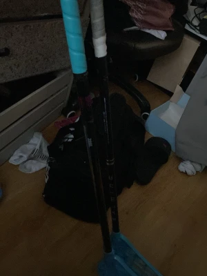 Två blåa innebandyklubbor - Säljer två innebandyklubbor med svarta skaft och blåa blad. Ena klubban har ett turkost grepp och den andra ett vitt grepp. Perfekt för dig som vill börja spela innebandy eller behöver extra klubbor till träningen.