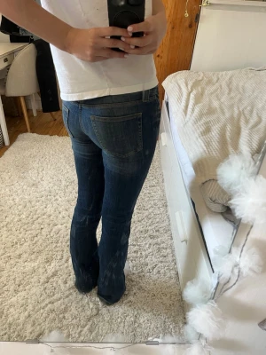 Mörkblå bootcut jeans - Säljer ett par mörkblå bootcut jeans med lätt slitning på framsidan och klassiska bakfickor. Jeansen har en snygg passform som sitter tajt över låren och släpper ut vid vaden. Perfekta till en avslappnad look och passar till det mesta.