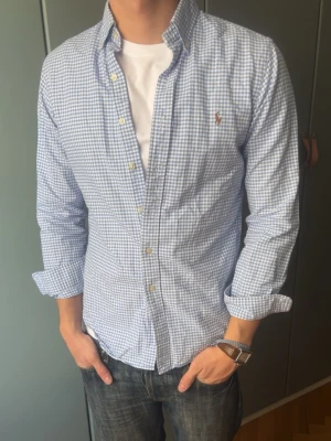 Blårutig skjorta från Ralph Lauren - Skjorta från Ralph Lauren, inga defekter. Modellen är 187 cm, väger 80 kg och brukar klä i M.  Storlek på skjorta S/P   Leverans sker dagen efter senast. Skriv om du har nån fråga✨ Axelmått:46 cm Längd: 70 cm  Byst: 48 cm Arm: 50cm (från armhåla) 57 cm (från axlar)