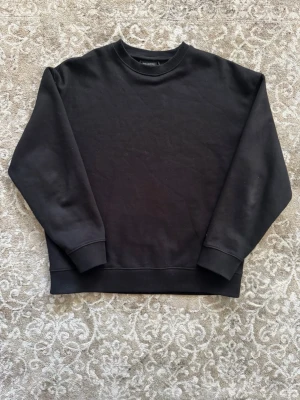 Svart sweatshirt från Pull&Bear - En stilren svart sweatshirt från Pull&Bear i storlek S. Tröjan har rund halsringning, långa ärmar och ribbade muddar vid ärmslut och nederkant. Perfekt för en avslappnad och trendig look.