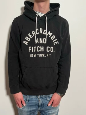 Vintage Abercrombie & Fitch hoodie - En svart vintage hoodie från märket Abercrombie & Fitch med text på framsidan. Passar perfekt nu till våren. Size S. Skick9/10. Modellen är 176cm lång väger 65kg.