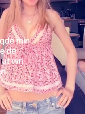 Rosa blommig linnetopp med spets - Supersöt rosa linnetopp med blommigt mönster och tunna axelband. Toppen har v-ringning och fina spetsdetaljer längs urringningen och nederkanten. 