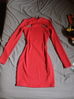 Röd ribbad cut out klänning - Röd ribbad klänning med långa ärmar och cut out-detaljer vid bröstet. Klänningen har en kroppsnära passform och någelunda hög hals. Perfekt för dig som vill sticka ut med en unik stil. Den passar perfekt till vardag, jul eller fester💕