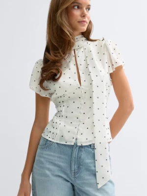 Vit prickig blus - vit blus med svarta prickar och korta, den har ett knytband vid halsen och en liten öppning framtill. Aldrig använd och prislappen kvar 