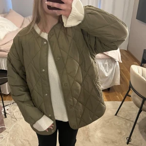 Olivgrön quiltad jacka - Quiltad jacka i olivgrönt med oversized passform och tryckknappar framtill.