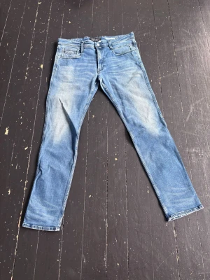 Blå slim fit jeans från Replay  - Snygga blå slim fit jeans med lätt slitna detaljer och klassisk femficksdesign. Jeansen har normal midja, dragkedjegylf och raka ben. Perfekta för en avslappnad och trendig look.