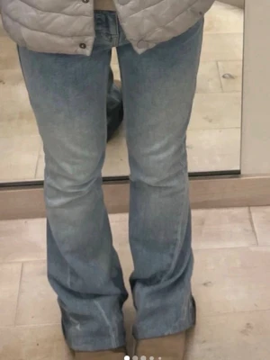 Ljusblå bootcut jeans True Religion - Säljer ett par ljusblå bootcut jeans från True Religion med klassiska kontrastsömmar och snygg broderad bakficka med knapp. Jeansen har normal midja och är tillverkade i denim med en lätt tvättad look. Perfekta för dig som gillar en avslappnad men trendig stil.  OBS nedre kant av byxan har gåtts på och därmed slitits