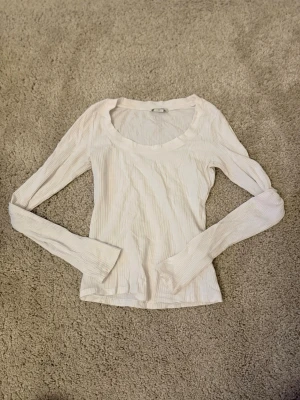 Vit ribbad långärmad topp Monki - Säljer en vit ribbad långärmad topp från Monki i storlek XS. Toppen har en rund urringad hals och är tillverkad i ett mjukt, stretchigt material som sitter snyggt på kroppen..