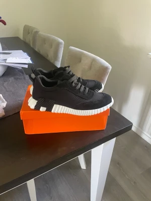 H skor  - Svarta sneakers med cool design och chunky vit sula. Skorna har snörning, ovandel i textil och detaljer i mocka. Snygga kontraster mellan svart och vitt gör dem till ett statement. Perfekta för dig som gillar streetstyle och vill sticka ut.