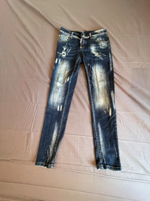 Dsquared2  skinny jeans - Mörkblå skinny jeans från Dsquared2 med slitningar, blekta partier och trasiga detaljer. Klassisk femficksmodell med gylf och knapp. Bakfickorna har tryck och en gul Dsquared2-label. Perfekta för en edgy streetstil.