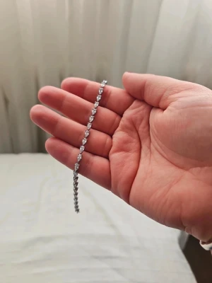 Mockberg Silver tennisarmband med stenar - Nypris ca 800 kr, prislapp sitter kvar. Ett elegant och stilrent tennisarmband i silverfärg med gnistrande, runda stenar längs hela bandet. Armbandet har en klassisk och tidlös design som passar perfekt till olika stilar. Perfekt accessoar för dig som gillar en glittrig detalj.