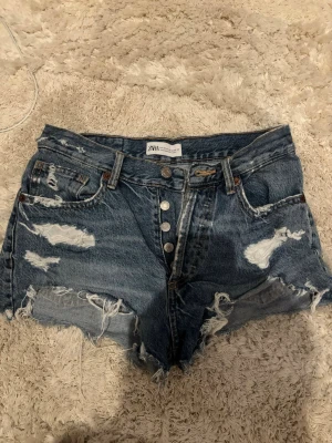 Blå slitna jeansshorts från Zara - Jättefina blå jeansshorts från Zara med medelhög midja och slitna detaljer. Jättesnygga nu till sommaren