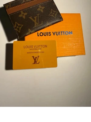 Louis Vuitton och Goyard plånböcker - Två exklusiva plånböcker: en brun Louis Vuitton i monogrammönstrat läder med bruna detaljer och en ljusblå Goyard i klassiskt mönstrat läder. Båda har tydliga loggor och levereras med originalask och kort. Perfekta accessoarer för dig som gillar lyxiga detaljer.