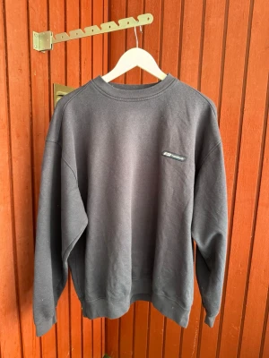 Mörkgrå sweatshirt från Reebok - En stilren mörkgrå sweatshirt från Reebok med klassisk rund halsringning och diskret logga på bröstet. Tröjan har en avslappnad passform och är tillverkad i mjukt bomullsmaterial. Perfekt för en chill och sportig look.