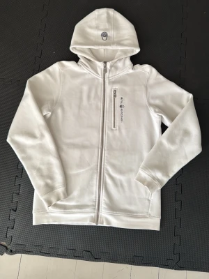 Sail Raicing Bowman Zip - Vit Sail Racing kofta. Jag har använt den men det har inga skador eller defekter. Fortfarande väldigt bra skick. Storlek 170