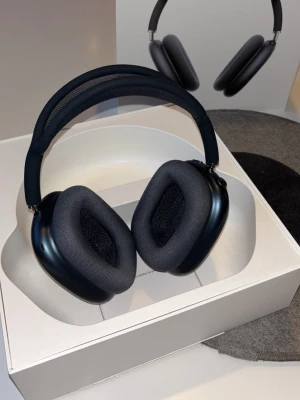 Apple AirPods Max ( Svart ) - Snygga over-ear hörlurar från Apple i mörkgrå färg. AirPods Max har en stilren design med mjuka öronkuddar i tyg och metallbyglar. Perfekta för dig som vill ha grymt ljud och modern look. Levereras med smart skyddsfodral.