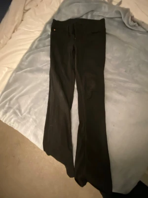Svarta utsvängda jeans från weekday - Svarta jeans från weekday med utsvängda ben och klassisk femficksdesign. Jeansen har en snygg rosa etikett med tigertryck bak i midjan och är tillverkade i ett stretchigt material för en bekväm passform. har andvänt dessa två gånger