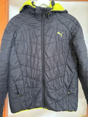 jacka från Puma - Svart pufferjacka från Puma med neongul insida. . Perfekt för kyliga dagar när du vill ha både stil och komfort.