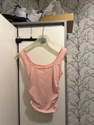 Ljusrosa ärmlös linnetopp - Söt ljusrosa linnetopp med breda axelband och rundad halsringning. Toppen är ärmlös och har en enkel, stilren design som passar perfekt till sommaren. Tillverkad i mjukt bomullsmaterial för en bekväm känsla.