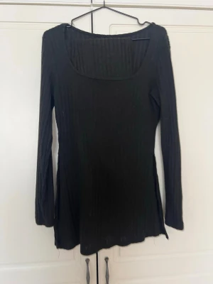 Svart ribbad långärmad topp - En svart långärmad topp med ribbad struktur och fyrkantig ringning. Toppen har en slim passform och är perfekt att styla med jeans eller kjol. Enkel och stilren design som funkar till många olika looks.💞💞🩷
