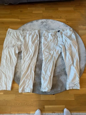 Beiga linnebyxor från H&M, Regular Fit - Två par beiga linnebyxor från H&M i Regular Fit. Byxorna har resår i midjan och dragsko för extra komfort. Tillverkade i ett lätt och luftigt linnematerial som passar perfekt för en avslappnad stil. Klassisk rak passform och neutrala färger.