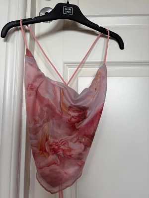 Rosa änglamönstrad linnetopp - Rosa linnetopp med änglamotiv och tunna axelband. Toppen har snygg snörning i ryggen och är gjord i ett tunt, lätt material som känns luftigt. 