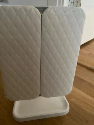 Vit sminkspegel med LED och förvaring - Stilren sminkspegel i vit plast med quiltat mönster på framsidan. Spegeln har vikbara dörrar och står på en praktisk fot med förvaringsbricka. Utrustad med LED-belysning och justerbart stativ för enkel användning vid sminkning.