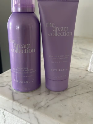 Rituals Dream Collection bodykit lila - Säljer ett set från Rituals The Dream Collection med en Pastel Sky Body Lotion Mousse (150 ml) och en Soft Glow Body Cream (100 ml). Båda i snygga lila förpackningar med doft av blue daisy och moonstone. Perfekt för dig som vill ha återfuktad och mjuk hud.
