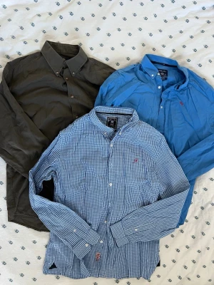 3 Stycken Herr Skjortor - Säljer 3 stycken herr skjortor. En blårutig skjorta från Robbie moor med klassisk button-down krage och långa ärmar. En blå också från Robbie moor och en khaki från McGordon. Alla i storlek XL. Måtten finns. 