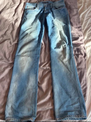 Ljusblå jeans från Nudie Jeans - Säljer ett par ljusblå jeans från Nudie Jeans med klassisk femficksmodell och raka ben. Tillverkade i bomull och har Nudie-loggan på bakfickan.