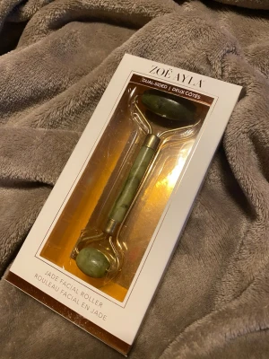 Jade Roller från Zoë Ayla - Dubbel­sidad ansiktsroller i grön jade från Zoë Ayla. Perfekt för att massera ansiktet och boosta hudvårdsrutinen. Kommer i obruten originalförpackning. 