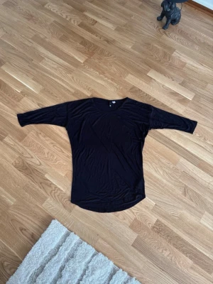 Topp H&M - Enkel svart topp med halvt långa armar. Tunt och mjukt material som känns skönt mot huden. Storlek 38 Har ett litet hål på baksidan, se sista bilden