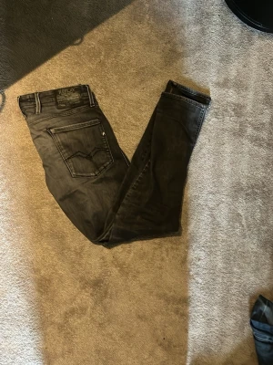 Svarta slim fit jeans från Replay - Säljer ett par svarta slim fit jeans från Replay, modell Anbass. Jeansen har klassisk femficksdesign, snygga sömmar och en skön stretchig känsla. Perfekta för dig som gillar en smalare passform och vill ha ett par stilrena jeans till garderoben.