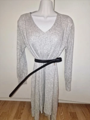Ljusgrå ribbad klänning med bälte - Ribbstickad klänning i grått med v-ringning. Klänningen kan bäras med eller utan tillhörande kofta, vilket ger den en mångsidig stil. Den har en smickrande passform som framhäver figuren. Vilket är ett signum för det japanska märket Snidel. Free size från XS - M 🤍 Nypris för båda ca 264 $  OBS: Skärpet ingår ej