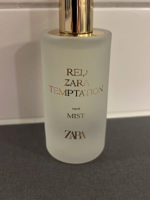 ZARA Red Temptation Hair Mist - Fräsch och lyxig hårmist från ZARA i serien Red Temptation. Flaskan är frostad i glas med gulddetaljer och elegant text. Perfekt för att ge håret en uppfriskande doft och extra glans.