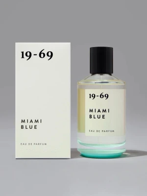 19-69 Miami Blue Eau de Parfum - Parfymen Miami Blue från 19-69 kommer i en stilren, genomskinlig glasflaska med svart lock och minimalistisk design. Doften är Eau de Parfum och flaskan har en ljusblå nyans i botten. Förpackningen är vit med svart text och matchar flaskans moderna look.