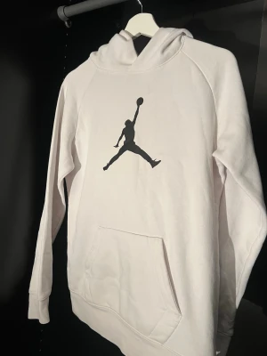 Vit hoodie från Jordan - Säljer en vit hoodie från Jordan med den klassiska svarta Jumpman-loggan på bröstet. Hoodien har känguruficka framtill och huva. Perfekt för dig som gillar sportig och clean stil. Den sitter vanligt på S storlek men kan sitta slim fit på M 