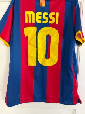 Barcelona Messi matchtröja Nike - Säljer en klassisk FC Barcelona matchtröja från Nike med Messi och nummer 10 på ryggen. Tröjan har blå och röda vertikala ränder, gula detaljer och klubbmärke på bröstet. Tillverkad i lätt och ventilerande material med Dri-FIT-teknologi.