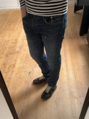 Mörkblå slim fit jeans Levis  - Säljer ett par mörkblå slim fit jeans med lätt slitna detaljer och klassisk femficksmodell. Jeansen har en snygg tvätt och sitter tajt längs benen för en modern look. Perfekta till vardagsoutfiten och passar till det mesta.