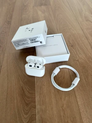 Apple AirPods 3 med laddningsetui - Säljer ett par vita Apple AirPods 3 med trådlöst laddningsetui och tillhörande USB-C laddningskabel. Snygg och stilren design i plast, perfekt för dig som vill ha grymt ljud och smidig anslutning till din iPhone eller andra Apple-enheter.