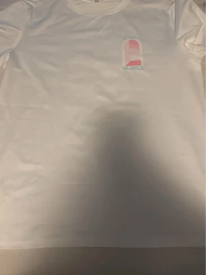 Vit Casa Blanca t-shirt med tryck - Snygg vit t-shirt från Casa Blanca med ett stilrent tryck i rosa och blått både fram och bak. Klassisk rund halsringning och korta ärmar. Tillverkad i mjuk bomull för skön känsla och enkel passform.