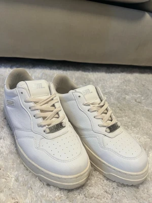 Vita Steve Madden sneakers i läder - Snygga vita sneakers från Steve Madden med klassisk låg silhuett. Skorna är tillverkade i läder med perforerade detaljer på tån och har vita snören samt metallbricka med Steve Madden-logga. Perfekta för en clean och stilren look.