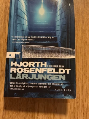 Lärjungen av Hjorth & Rosenfeldt - Spännande kriminalroman av Hjorth & Rosenfeldt med omslag i blå toner och motiv av en trappa och en kniv. Perfekt för dig som gillar deckare med nervkittlande handling. Pocketbok med tydlig titel och författarnamn på framsidan. Andra boken i serien. 