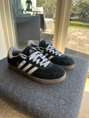 Adidas Spezial - Ett par svarta Adidas Spezial sneakers med vita snören och vita ränder på sidorna. Skorna har en brun sula och Adidas-logotypen syns på plösen och innersulan.  Super fina knappt använda står o bara o ta massa plats  Storlek 39-1/3  Tveka inte att höra av er vid frågor!