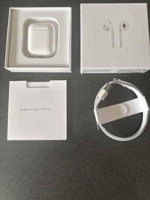 Apple AirPods med laddningsetui - Är öppen för bud Säljer ett par vita Apple AirPods med trådlöst laddningsetui. Snygg och stilren design i blank plast, perfekt för dig som vill ha smidiga hörlurar till mobilen. Kommer med originalkartong, laddkabel och instruktioner.